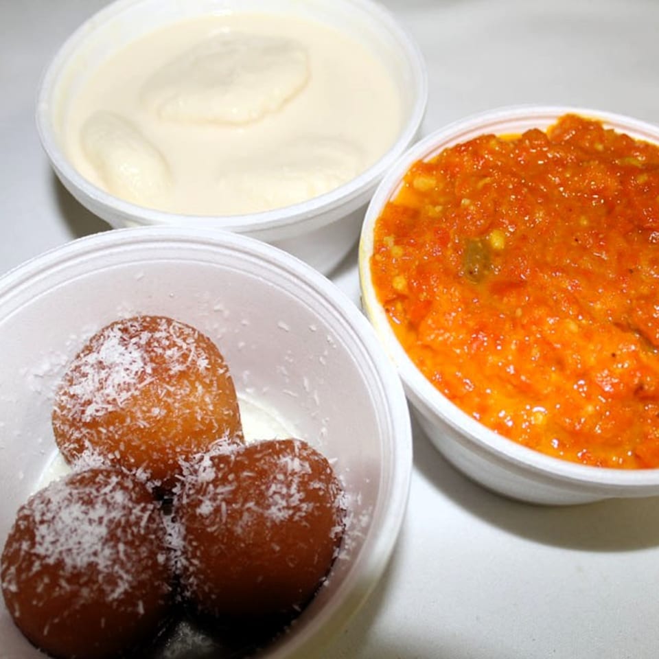 Three Indian desserts: gulab jamun with coconut, rasmalai, and gajar ka halwa in white bowls.