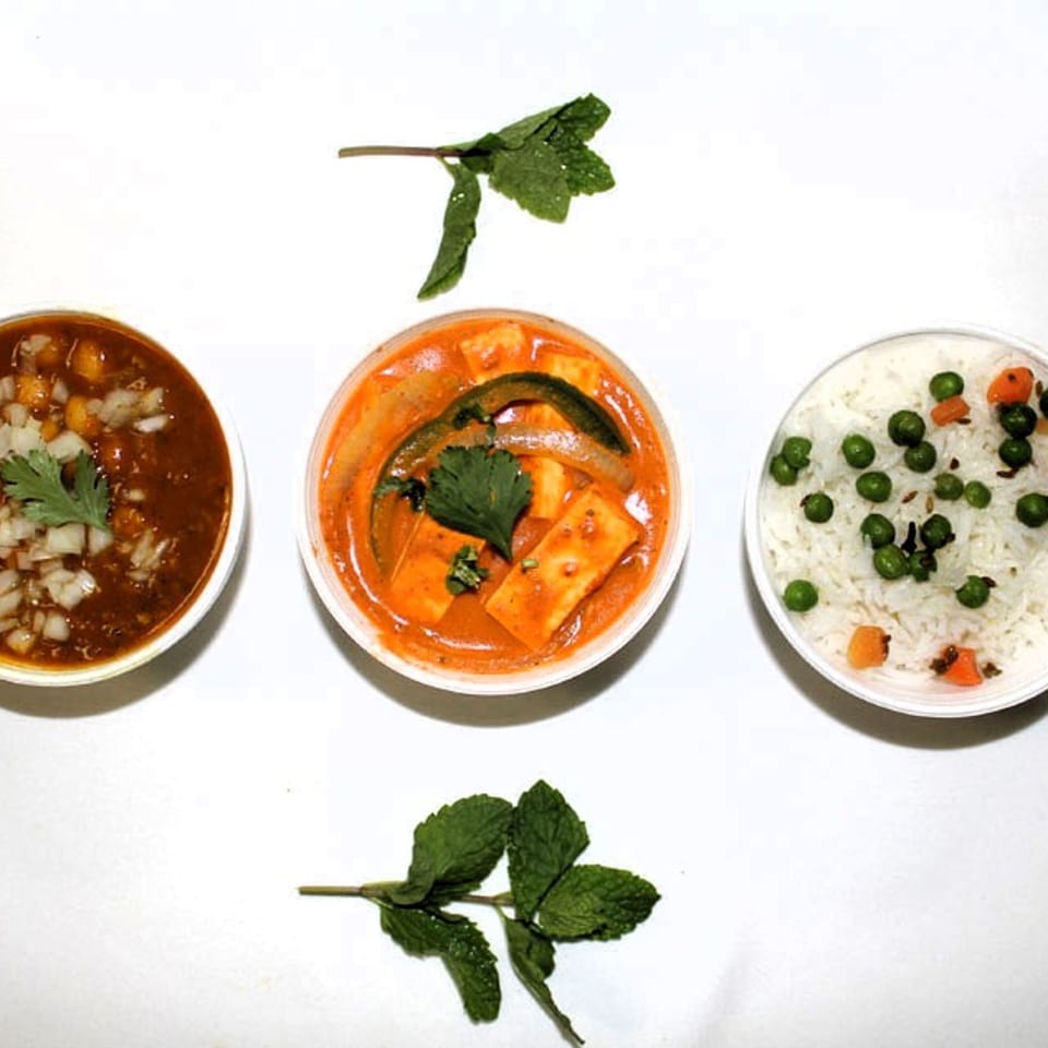 Three Indian dishes: chana masala, paneer curry, and pea pulao rice, garnished with mint.